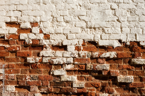 Old painted brick wall with crumbling elements. Uneven textured surface. Design element for historical almanac or album