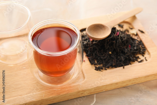 Wooden board with cup of black tea on grunge background, closeup