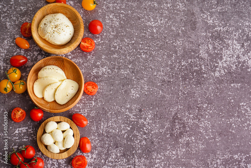 Composition with bowls of tasty mozzarella cheese and tomatoes on grunge background