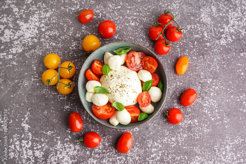 Bowl of delicious mozzarella cheese with tomatoes on grunge background