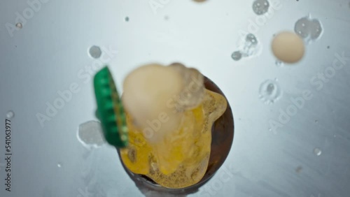 Uncorking bottled craft beer closeup. Unfiltered liquid splashing from flask photo