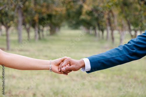 Novios sosteniendo las manos en su boda en el bosque 