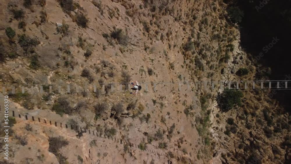 Self improvement, a man crosses a suspension bridge, bird's eye view, equipped with climbing equipment Self improvement, a man crosses a suspension bridge, bird's eye view, equipped with climbing equipment