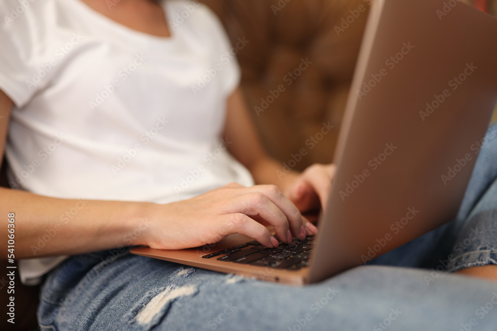 Naklejka premium Woman typing on modern laptop with sticker on cover