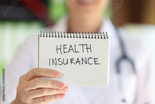 Female hand holding notepad with health insurance lettering