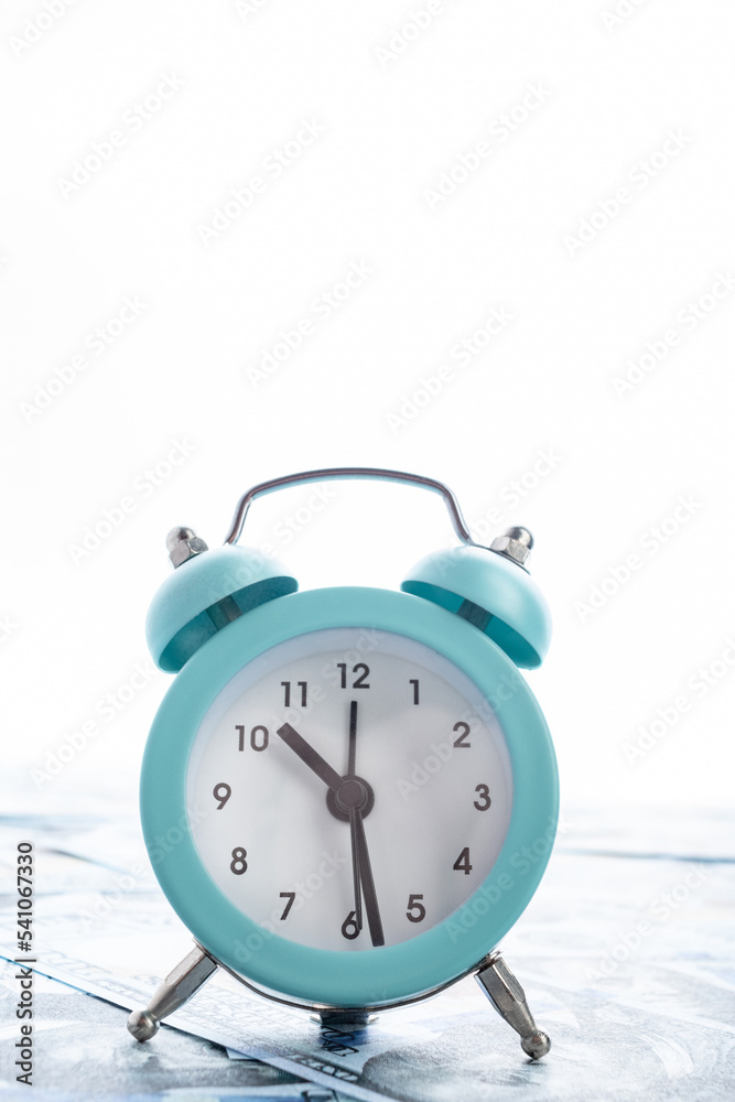 A small alarm clock stands on dollar bills. A small alarm clock stands on dollar bills.
