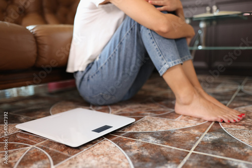 Woman sitting on floor near electronic scales