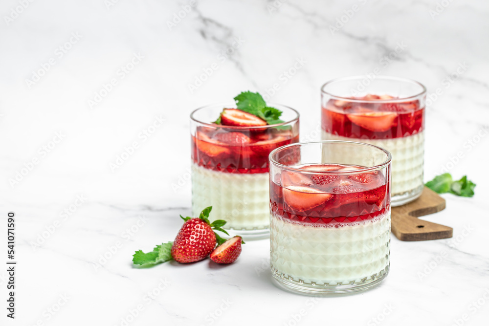 Italian panna cotta dessert with strawberry and mint on a light background. Summer yogurt dessert. space for text Italian panna cotta dessert with strawberry and mint on a light background. Summer yogurt dessert. space for text