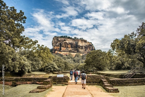 Fotografie Group of tourists walking to the Sigiriya against a cloudy sky in Sri Lanka