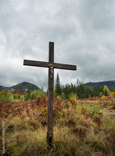 Christian cross in the mountains among bright autumn vegetation.