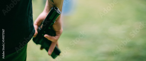 A firearm in a person's hand. Close-up. The man hides a gun in his hand