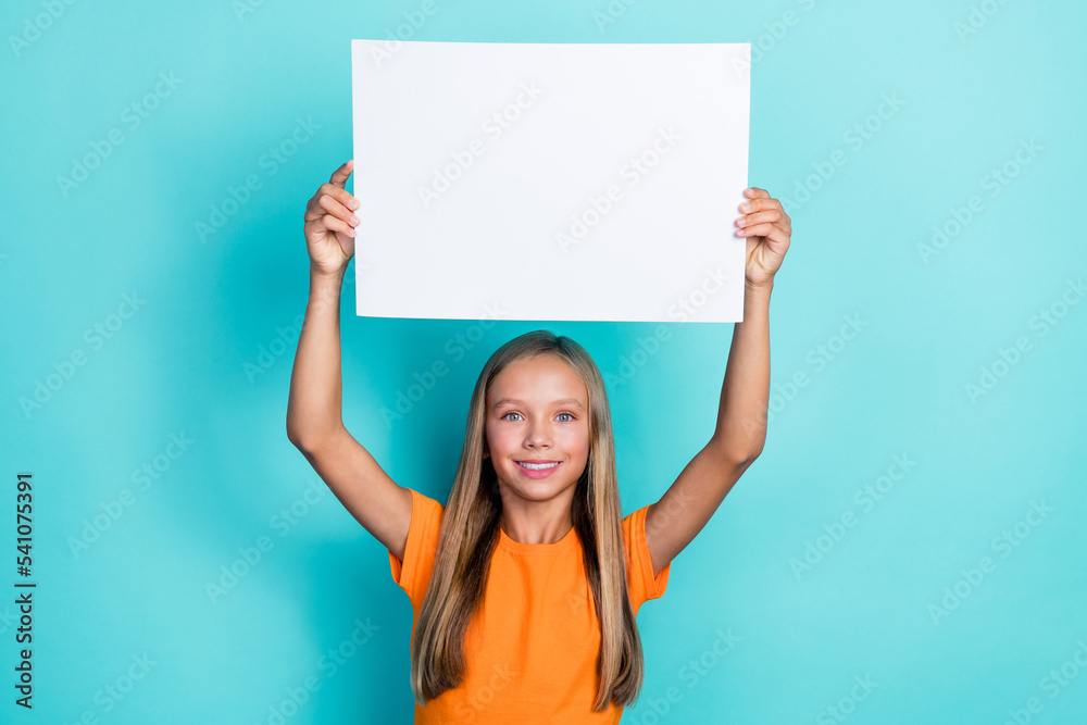 Photo of cute little schoolgirl kid blonde hair hold big paper white banner positive smiling enjoy new advertisement isolated on cyan color background Photo of cute little schoolgirl kid blonde hair hold big paper white banner positive smiling enjoy new advertisement isolated on cyan color background