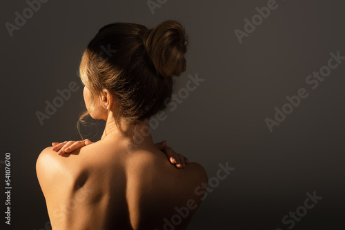 Fototapeta back view of nude woman with perfect body touching shoulders isolated on grey