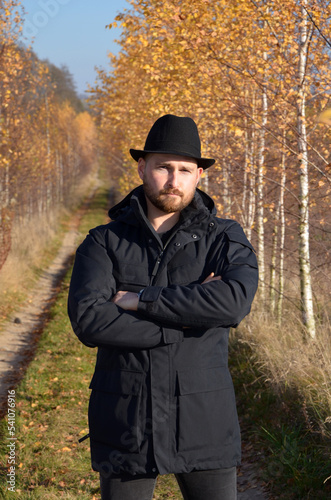 portrait of a man in a hat against the background of autumn trees