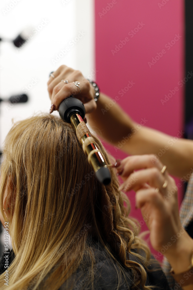 Fototapeta premium mano de peluquera peinando el pelo con maquina de rizos