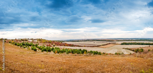landscape of farmland in autumn with colorful trees and dramatic sky