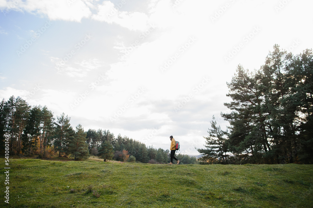 A hiker walking in nature carrying backpack A hiker walking in nature carrying backpack