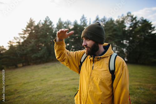 Horizontal portrait of hiker young male hiking in mountains with travel backpack. Traveler man with beard trekking and mountaineering. Travel, people, healthy lifestyle concept