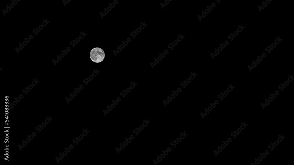 The full moon in the dark sky illuminates the earth