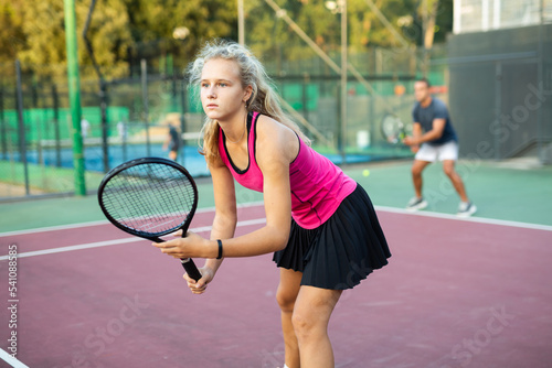 Focused young woman playing tennis on court, preparing to hit forehand to return ball. Concept of sport training © JackF