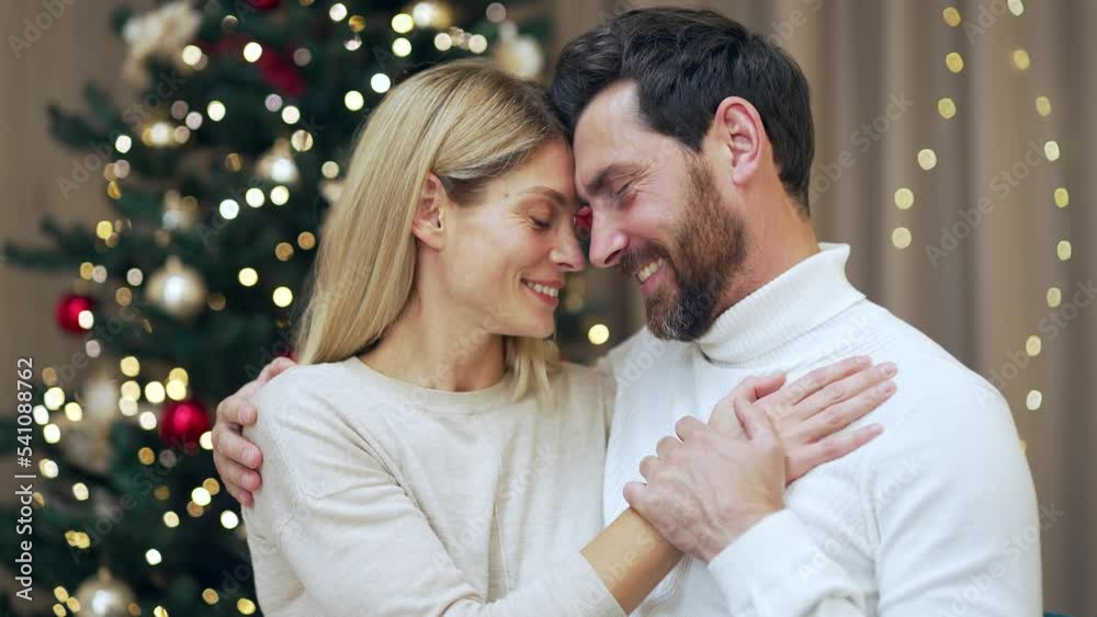 Married couple hugs on Christmas Eve or New Year holidays in cozy house indoors at home Evening. Caucasian Lovers Man and woman embrace. Closeness of husband and wife love and happiness Married couple hugs on Christmas Eve or New Year holidays in cozy house indoors at home Evening. Caucasian Lovers Man and woman embrace. Closeness of husband and wife love and happiness