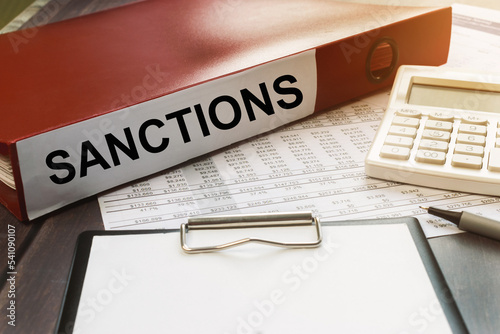 A red folder labeled sanctions. The concept of politics and economics. Crisis
