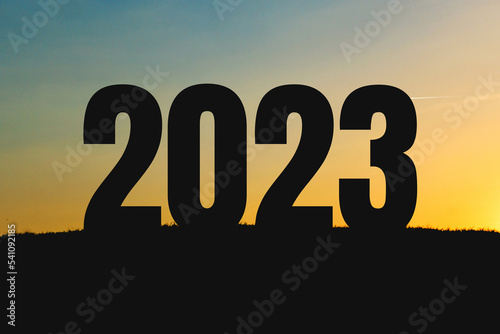 New Year 2023 in the field at sunset. Poster for the calendar. Shadow of numbers 2023