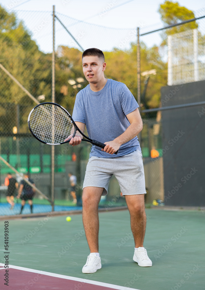 Concentrated young man tennis player hitting ball with a racket