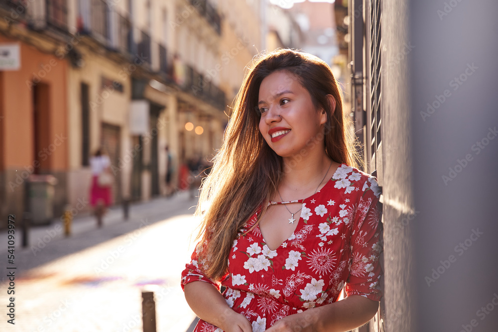 portrait of a young latina woman on the street in a city with the sun's rays shining on her hair