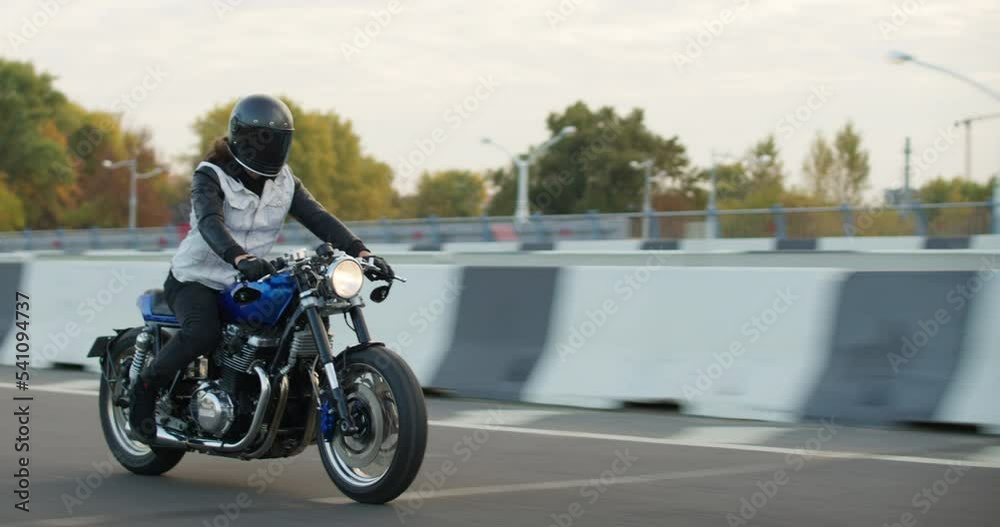 Driving Bike on Streets. Speed Motion in Cityscape. Fast TRACKING Shot of a biker riding his custom built cafe racer motorcycle through city. Motorcyclist Drives on Motorcycle on Road Driving Bike on Streets. Speed Motion in Cityscape. Fast TRACKING Shot of a biker riding his custom built cafe racer motorcycle through city. Motorcyclist Drives on Motorcycle on Road
