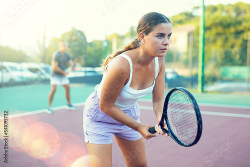 Expressive resolved fit girl playing tennis ball friendly match on outdoors court © JackF