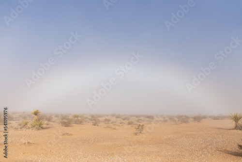 Winter weather phenomenon fog bow or white rainbow caused by sunlight meeting moisture and refracting light captured on cold December day within the Mojave desert