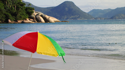 colorful beach umbrella with sea, stones and mountain on background - Summer in Florianópolis, Brazil 