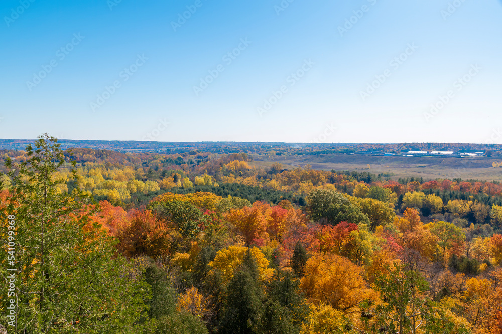 The sun beams brightly over the Autumn coloured foliage around Milton, Ontario, as seen from Rattlesnake Point Conservation Area.