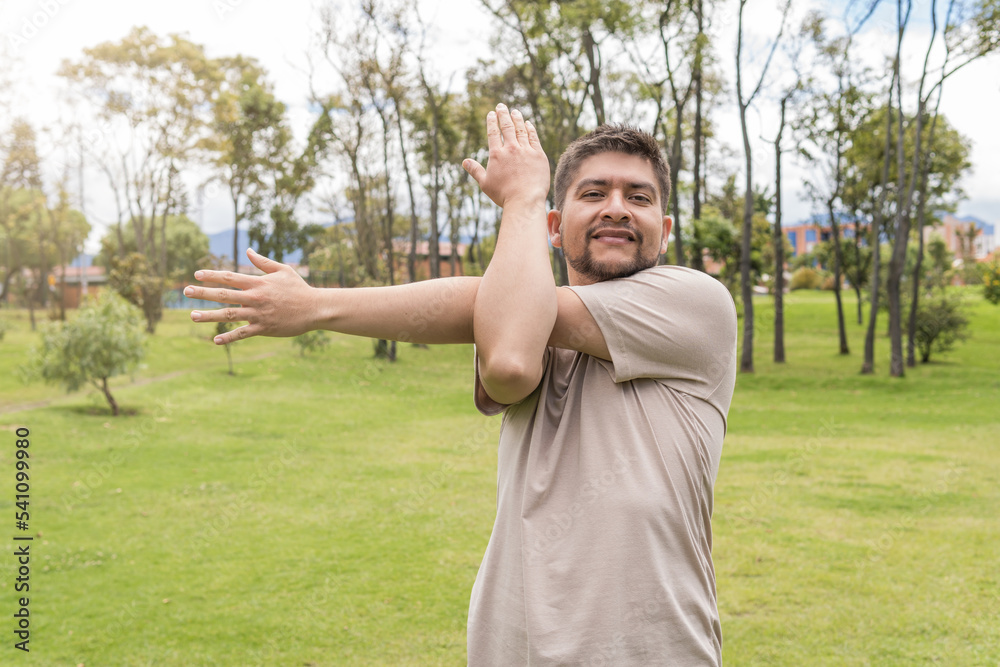 man stretching his arms to exercise in the park