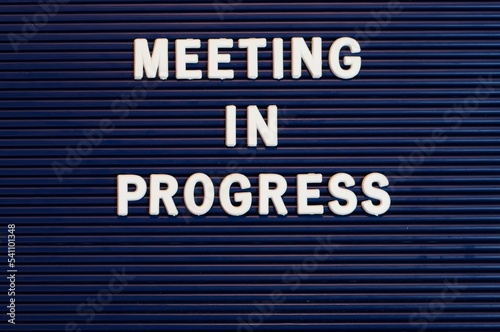 Pushboard sign that says meeting in progress in plastic letters photo