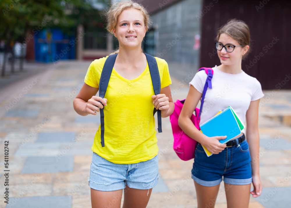 Portrait of two female students walking down the street to college