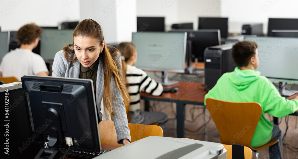 Fototapeta premium Female teacher working on computer in computer class