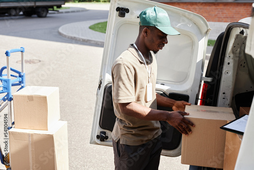 Side view portrait of young African American man unloading delivery van with boxes © Seventyfour