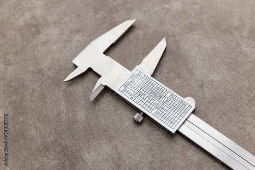 Opened jews metal vernier caliper with measurement conversion table on the rusty grunge background	