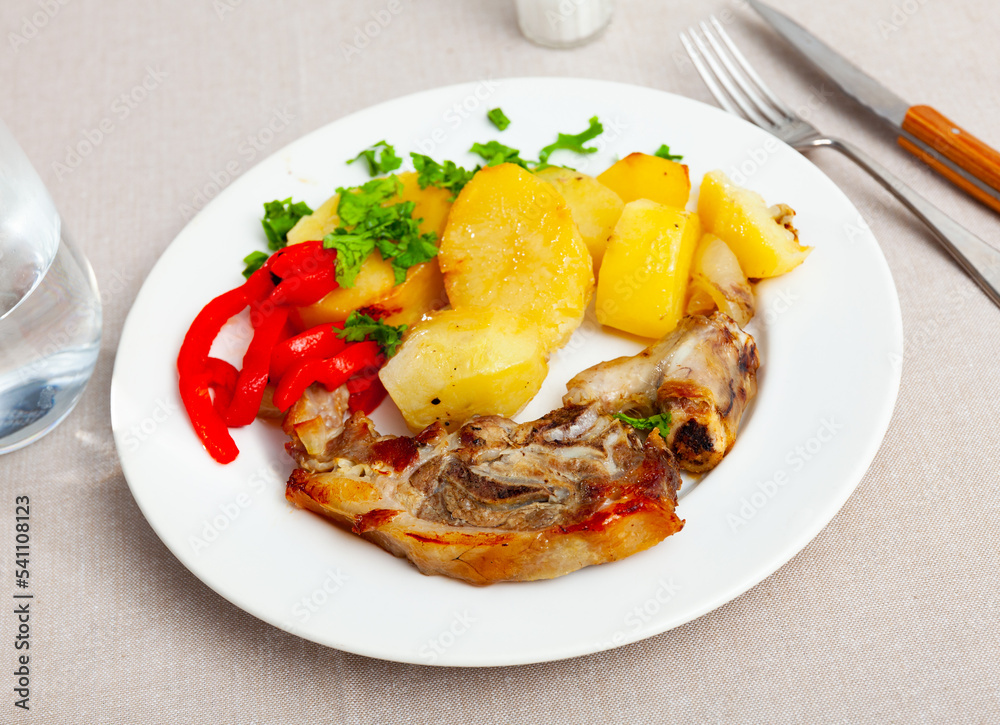 Portion of roasted lamb leg with potatoes and pepper served on plate.