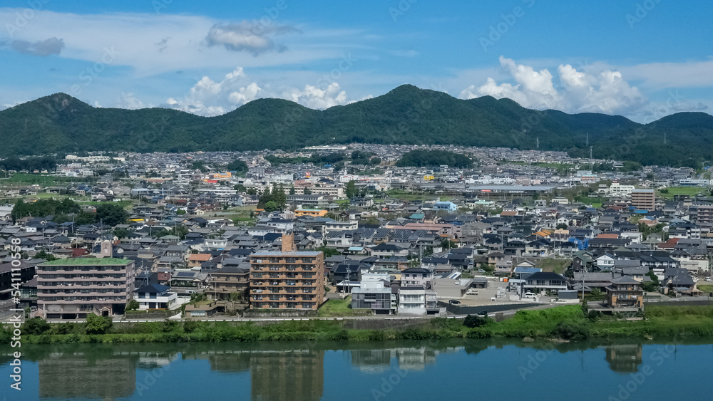 Aichi, Japan - September 10 2022:  Cityscape of Inuyama City, Kiso river and hills taken photo from Inuyama Castle with blue sky and clouds background.