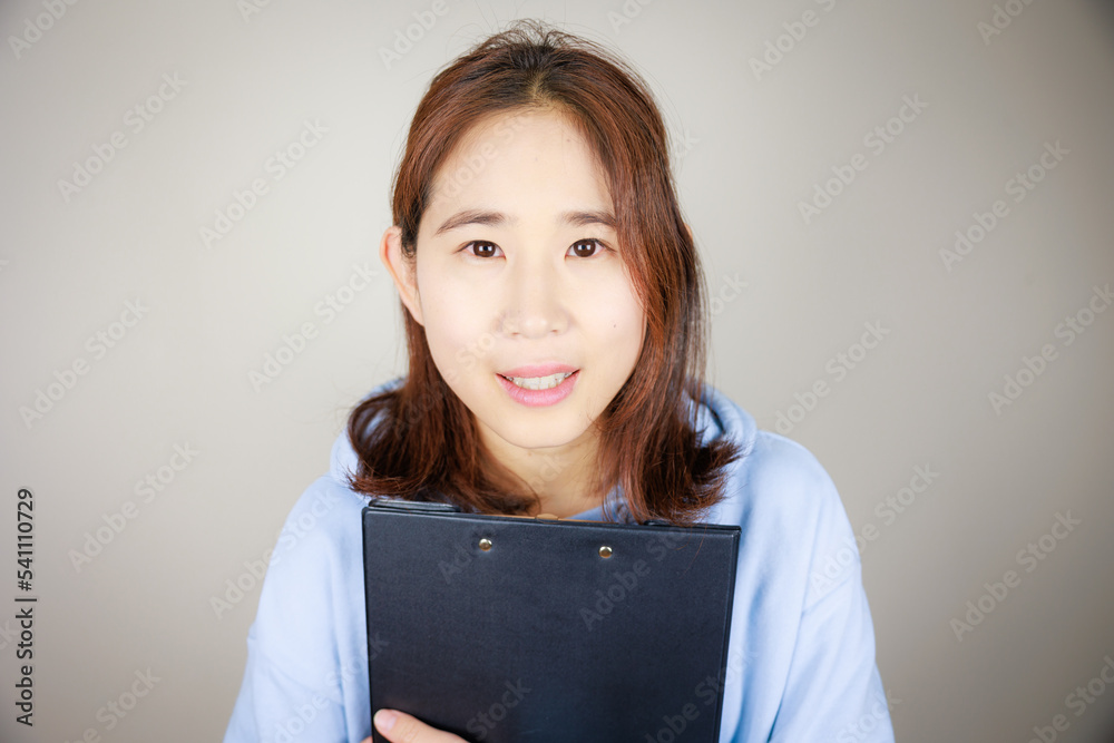 ファイルを持って正面から覗き込む女性 ファイルを持って正面から覗き込む女性