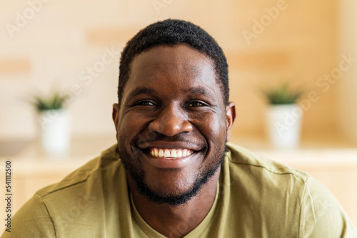 portrait of cheerful happy young man with in casual white t-shirt at home