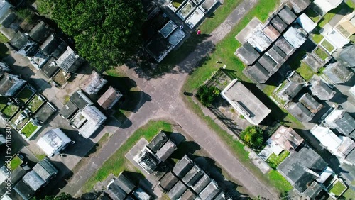 Aerial: Aerial Top Panning Shot Of People By Tombstones In Graveyard, Drone Flying Upwards On Sunny Day - New Orleans, Lousiana photo
