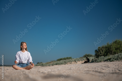 Girl practice meditation on the beach. With space for text or design © grthirteen