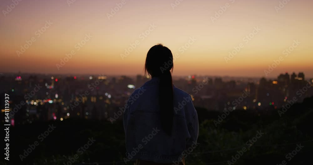 Back rear view of woman look at the city under sunset