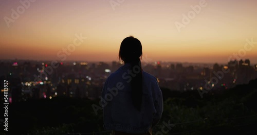 Back rear view of woman look at the city under sunset