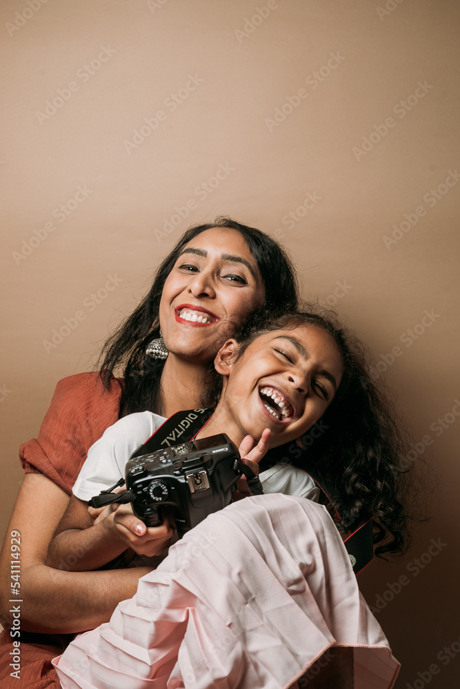 Mom and daughter smiling with daughter holding a camera 