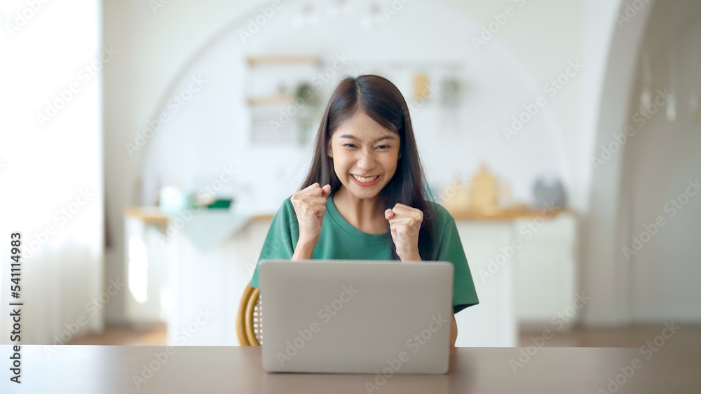 Funny euphoric young asian woman celebrating winning or getting ecommerce shopping offer on computer laptop. Excited happy girl winner looking at notebook celebrating success Funny euphoric young asian woman celebrating winning or getting ecommerce shopping offer on computer laptop. Excited happy girl winner looking at notebook celebrating success